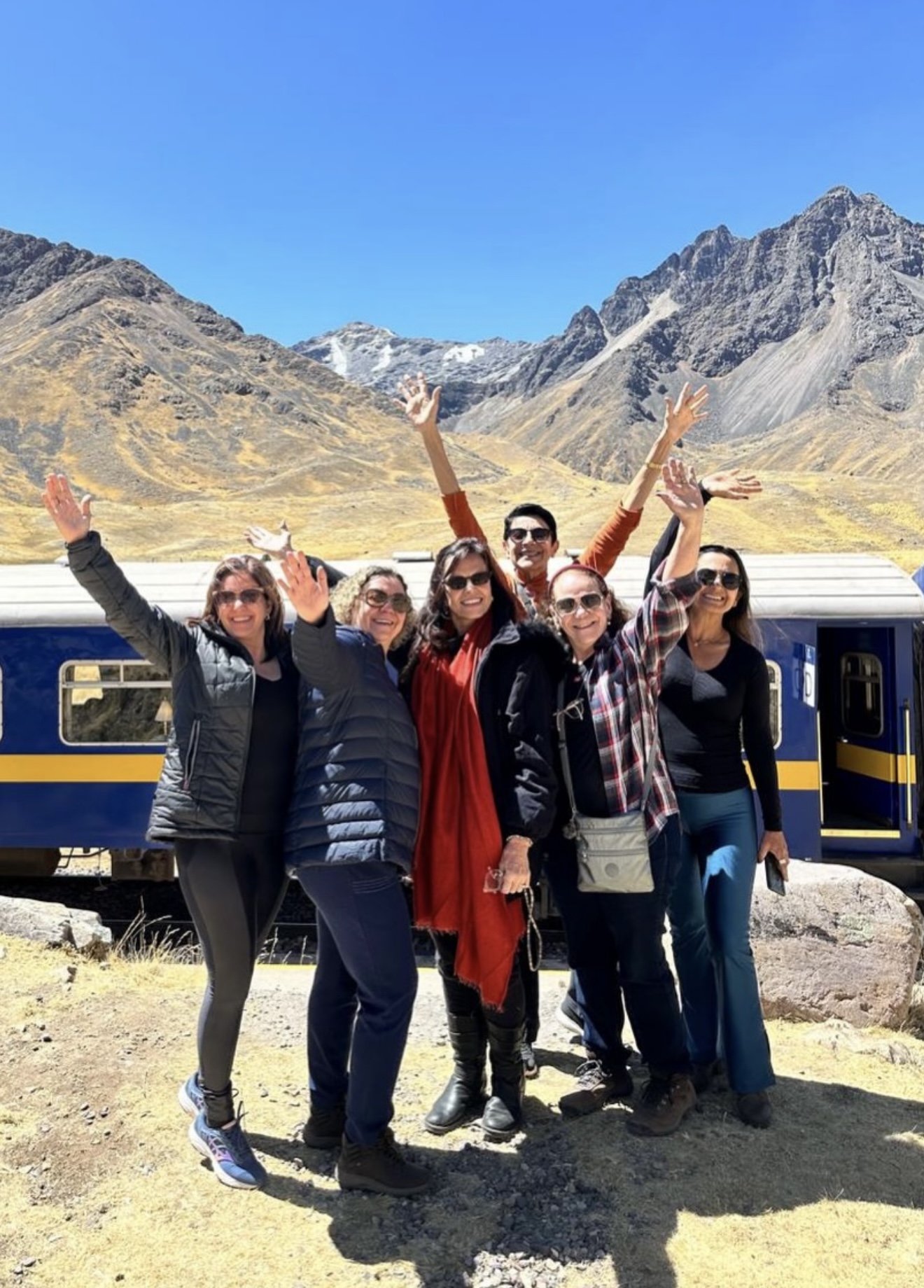 Grupo de mulheres no Peru, em frente ao trem nos Andes